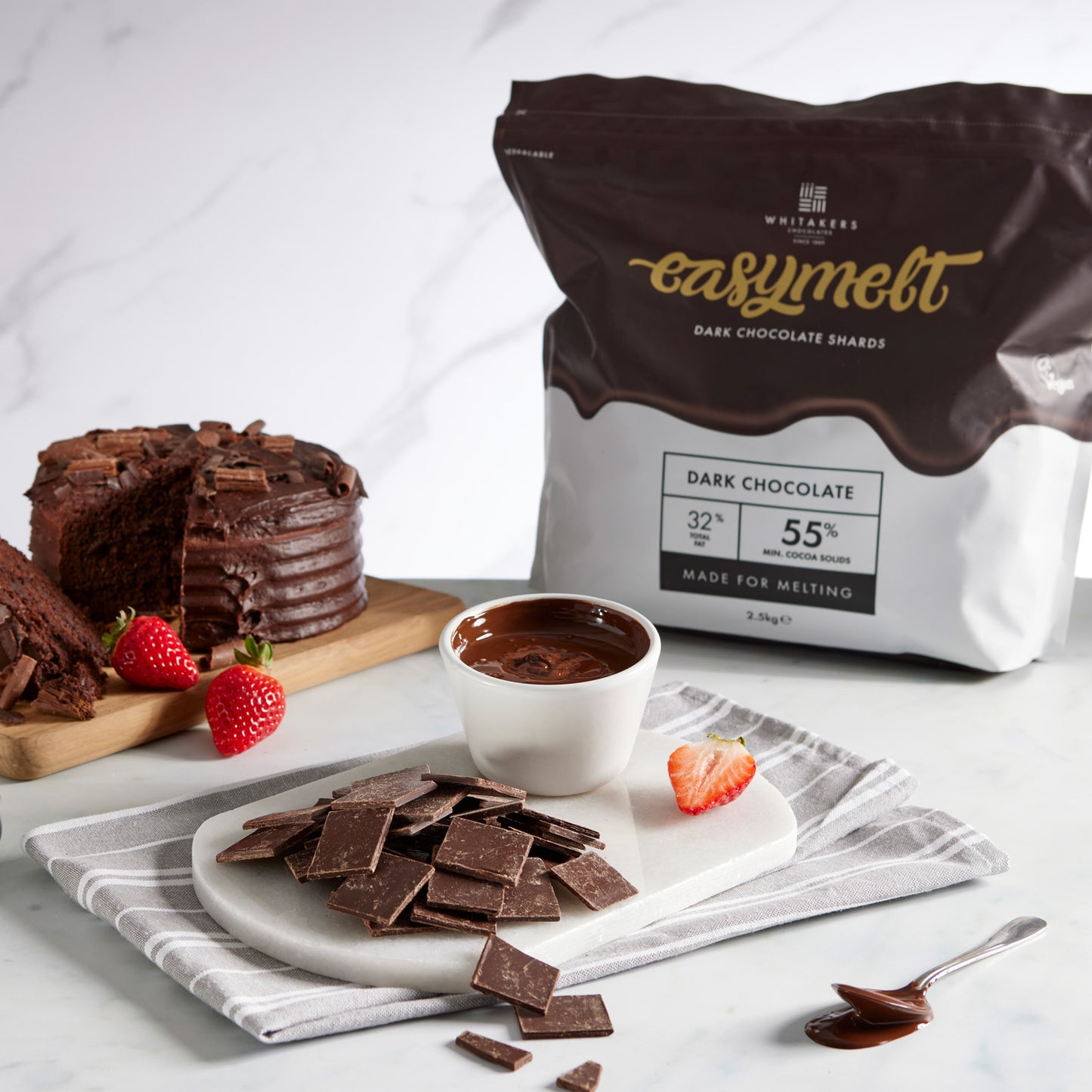 55% dark chocolate mini shards lifestyle shot with a chocolate cake, strawberries and melted dark chocolate