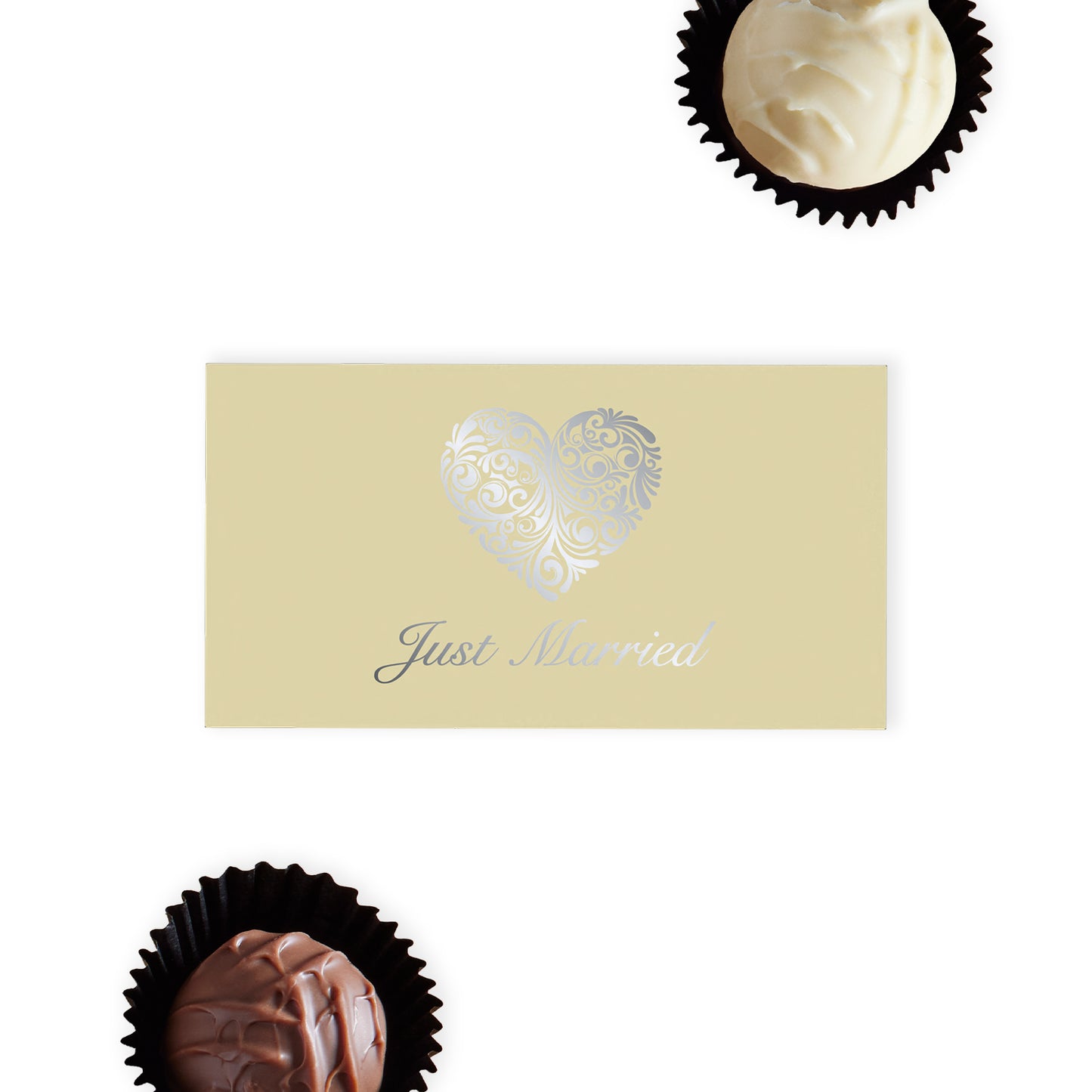 "Just Married" Chocolate Gift Box, an exquisite offering that pairs elegance with indulgence.  This cream-coloured gift box is beautifully adorned with an ornate silver heart and stylish "Just Married" font on the top, making it a standout addition to any wedding celebration.  Inside, discover two delicious hand-finished truffles, one milk and one white chocolate