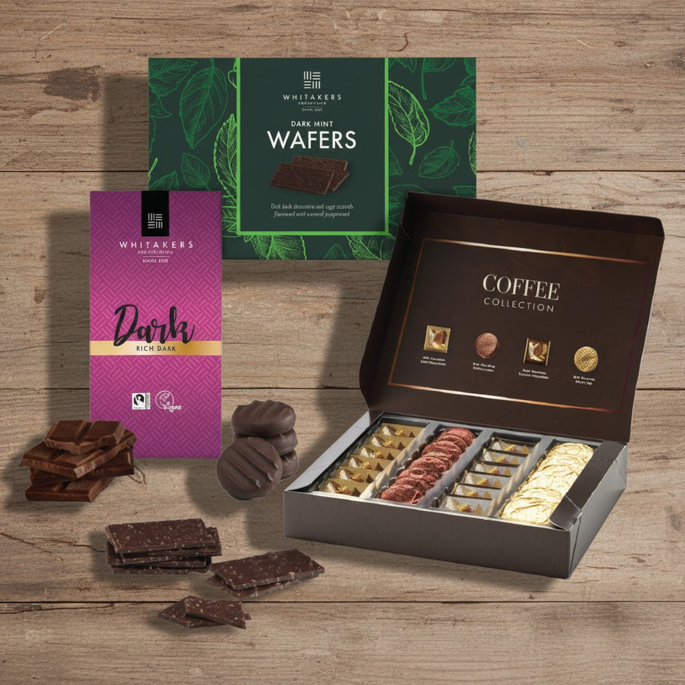 Whitakers Chocolates assorted chocolate selection, containing dark mint wafers, dark chocolate bar and milk and dark chocolate coffee collection box on a wooden surface