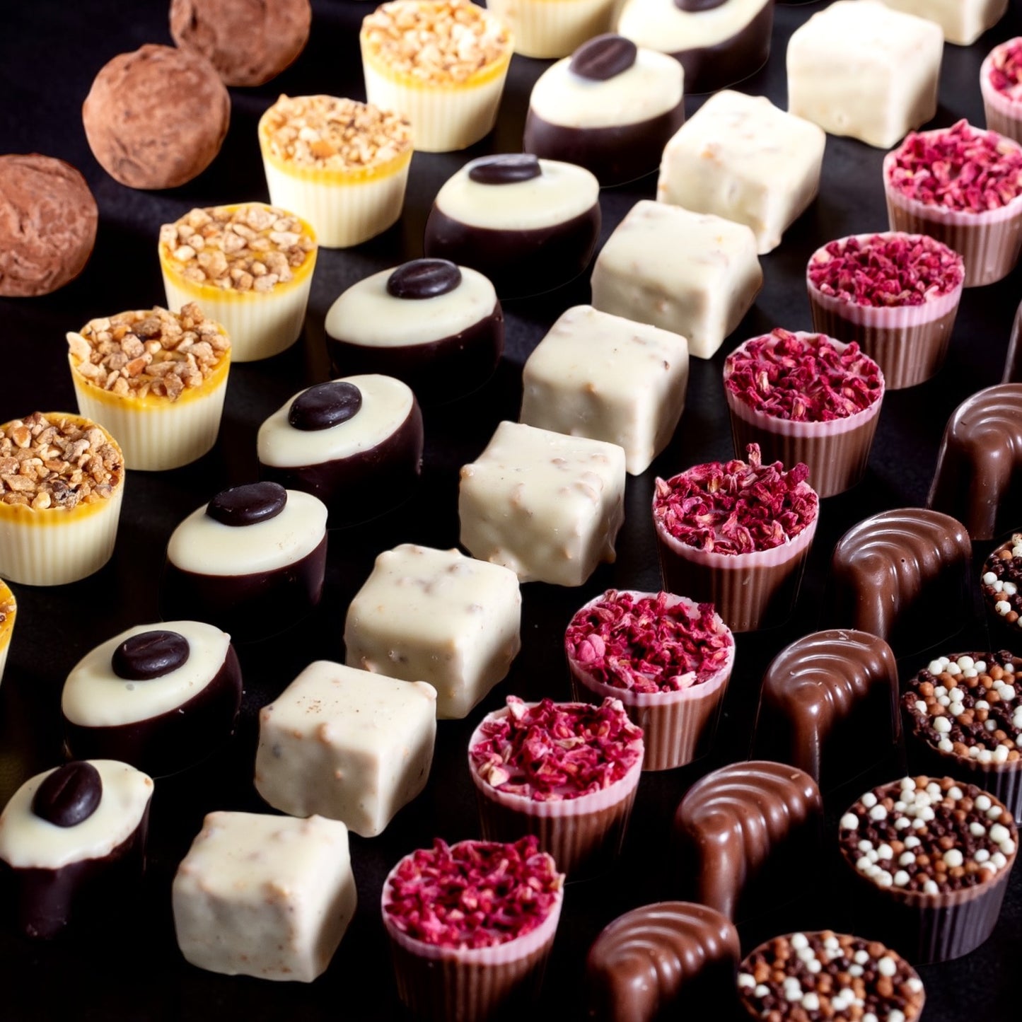Assorted handmade chocolates and truffles on a dark background