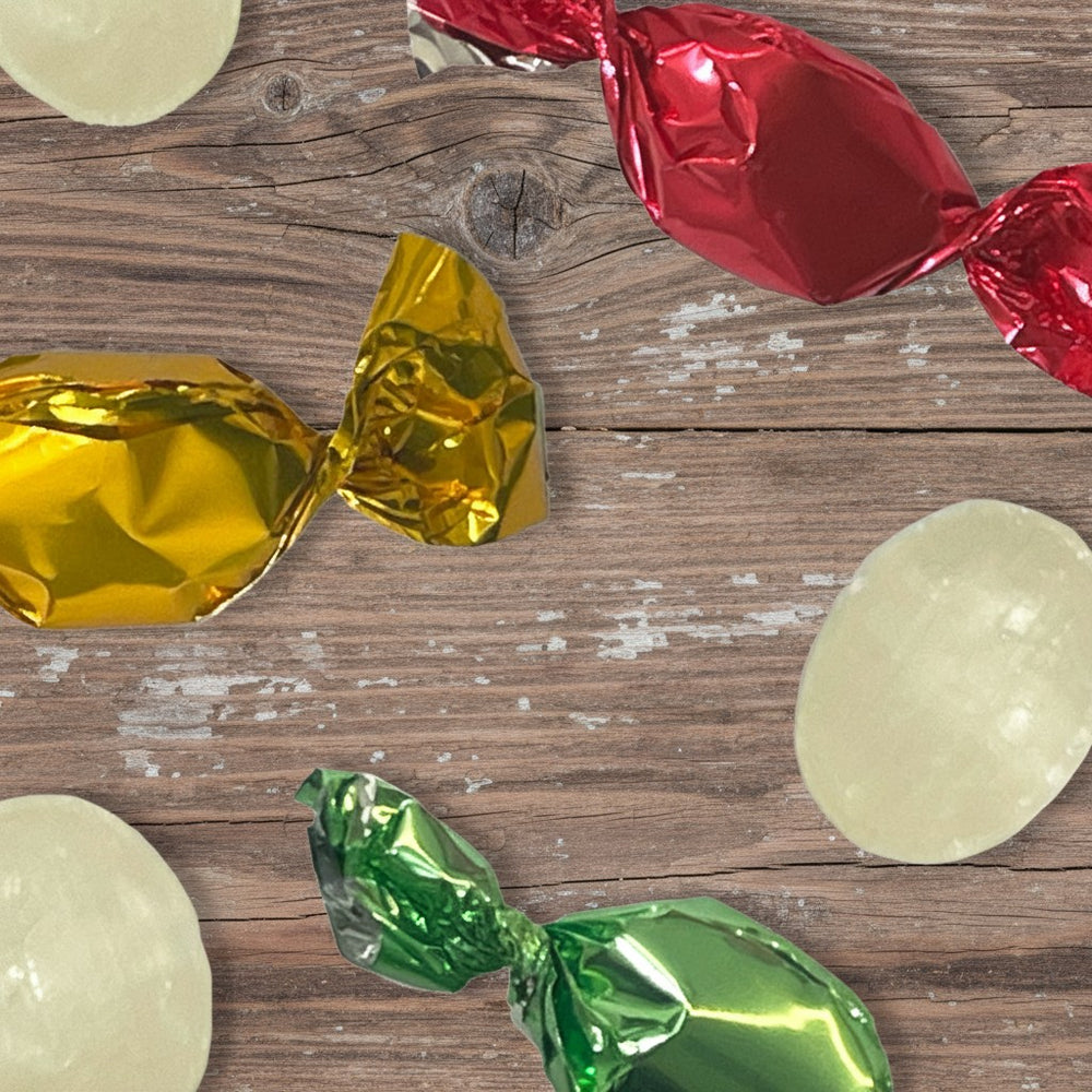 Candies with gold, red, and green wrappers on a wooden surface