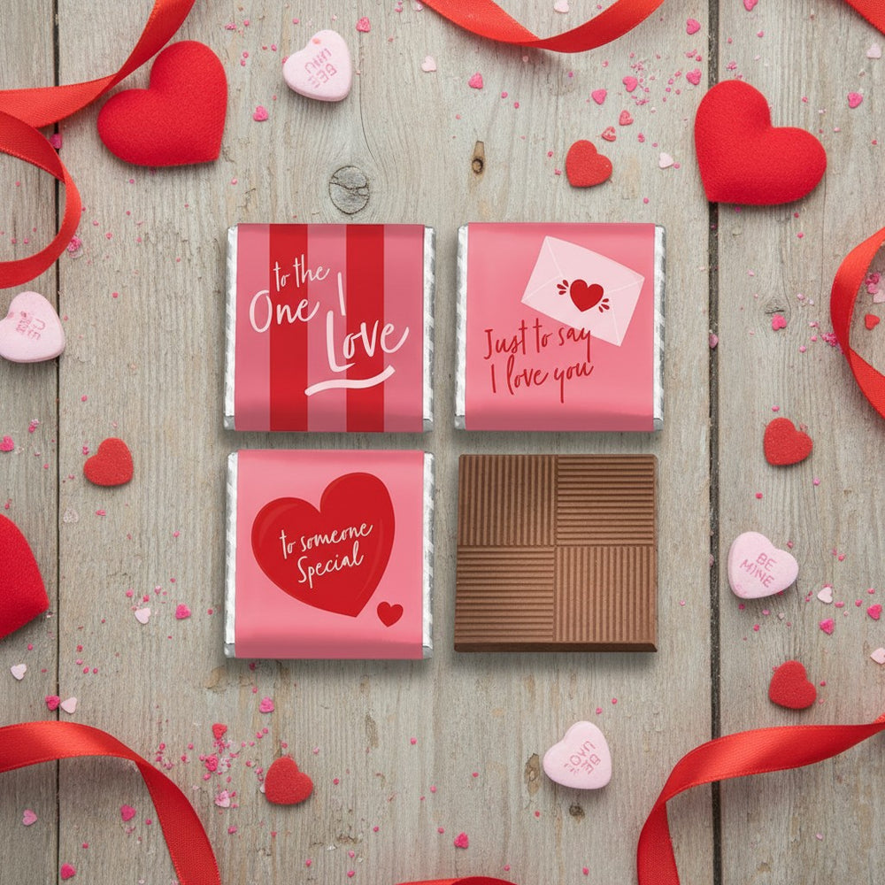 Four milk chocolate squares with Valentine's Day-themed packaging on a white background