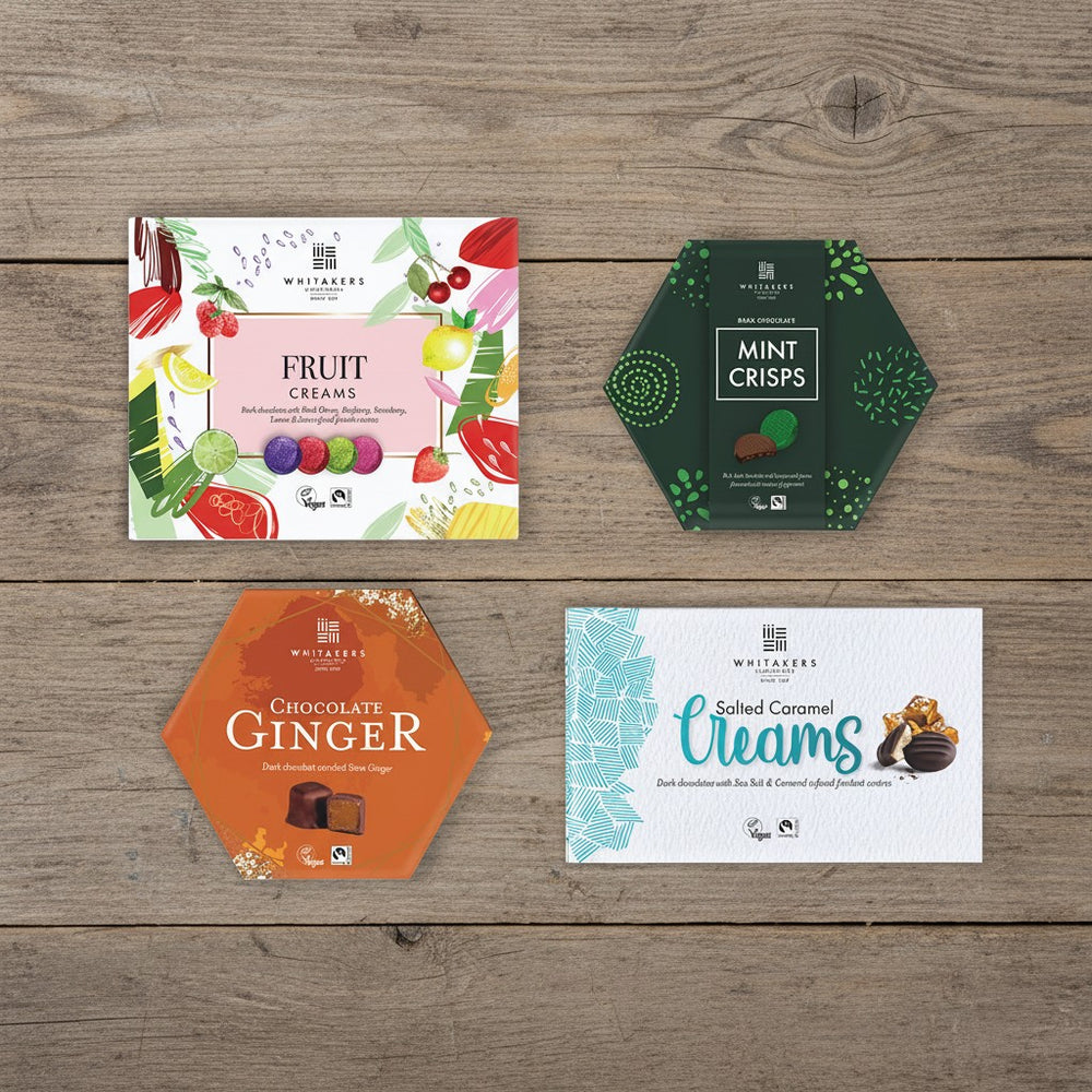 Four Whitaker's chocolate packaging on a wooden surface (fruit creams, mint crisps, chocolate gingers, salted caramel creams).