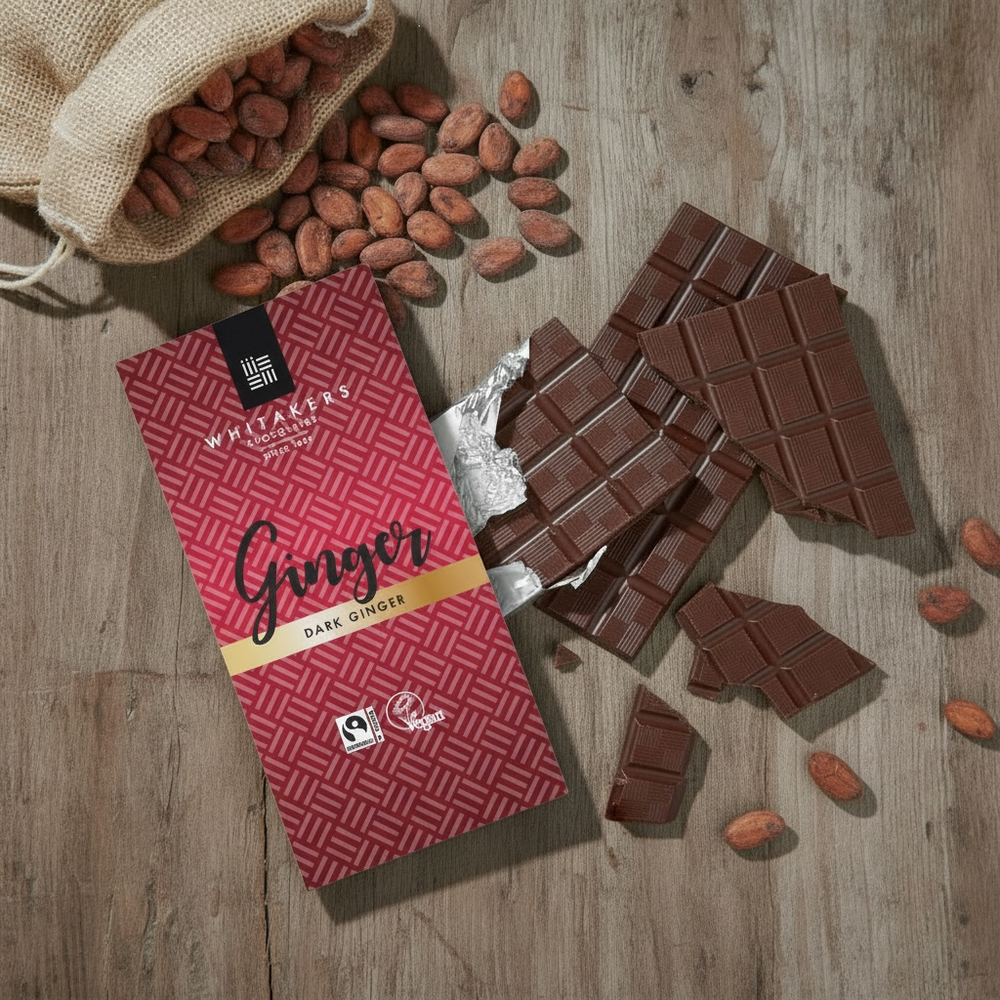 Whitaker's Dark chocolate 90g bar on a rustic wooden background with cocoa beans and broken chocolate
