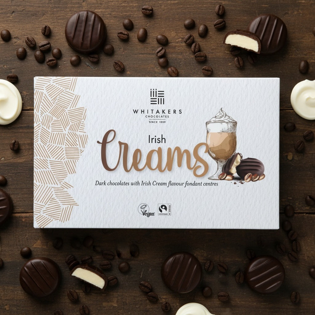 Whitaker's dark chocolate Irish Creams chocolate box on a wooden surface with chocolate pieces and coffee beans.
