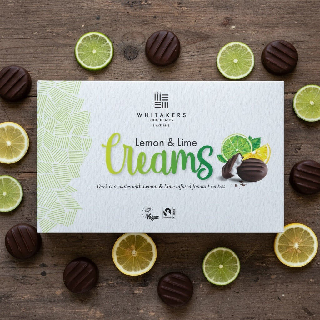 Whitaker's dark chocolate Lemon & Lime Creams chocolate box on a wooden surface with lemon and lime slices.
