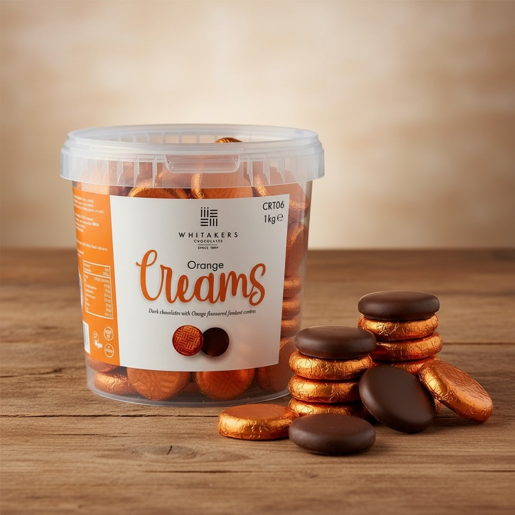 Tub of Whitakers Orange foiled dark chocolate orange creams on a wooden surface